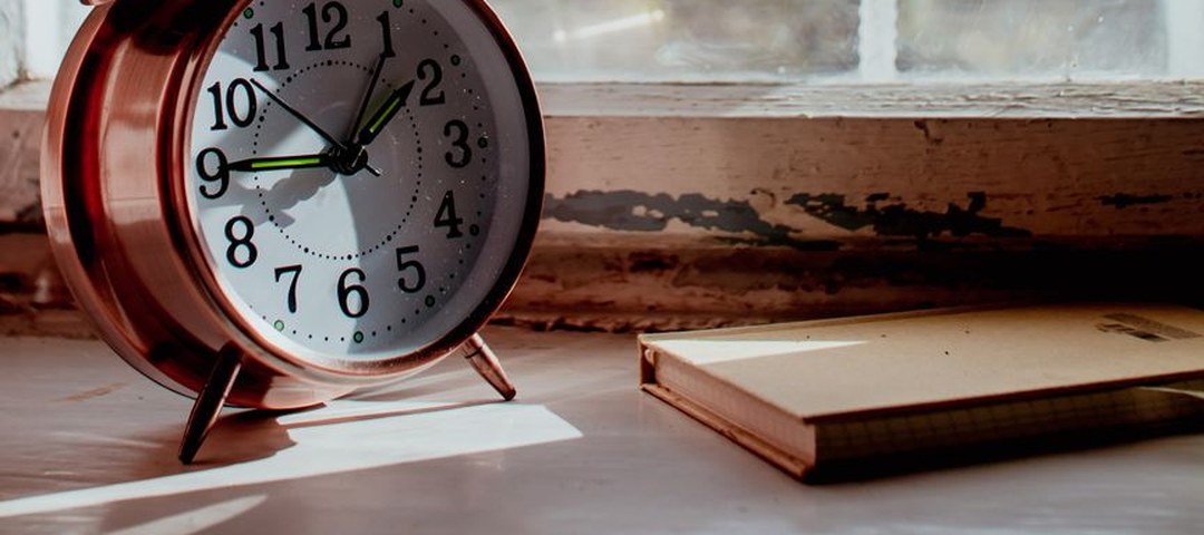 Réveil au petit matin près d’une fenêtre lumineuse — se préparer au changement d’heure Réveil au petit matin près d'une fenêtre lumineuse — se préparer au changement d'heure